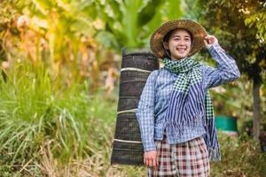 joven bonito granjero mujer en pie en tierras de cultivo y inspeccionando agrícola cultivos foto