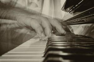 manos jugando piano mientras Moviente en sepia foto