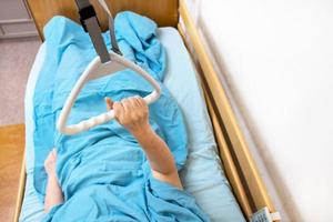 hand of sick woman holds handle of hospital bed photo