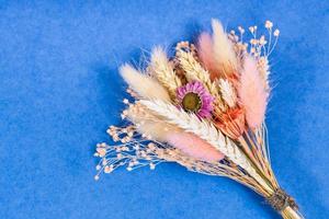 tied bouquet of dried flower and spikelets on blue photo