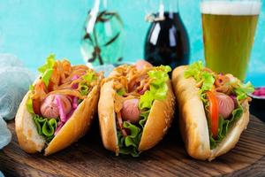 Hot dog with lettuce, tomatoes and pickled onions. Grilled bun with sausage photo