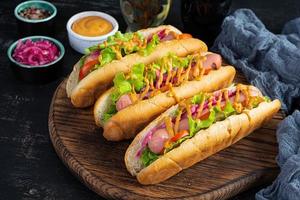 Hot dog with lettuce, tomatoes and pickled onions. Grilled bun with sausage photo