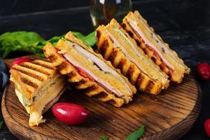 Club sandwich with ham, cheese, tomato and salad. Grilled sandwich with dried tomatoes bread photo