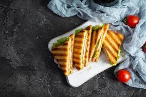 Club sandwich with ham, tomato, green and cheese. Grilled panini. Top view photo