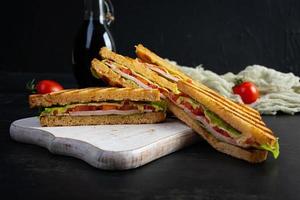 Club sandwich with ham, tomato, green and cheese. Grilled panini photo