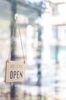 The store open sign is installed around the glass door in front of the store so that customers can see the store open sign and come to use the service in the coffee shop, startup business concept. photo