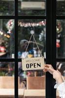 Coffee shop employees are flipping store opening sign installed on glass front door so that customers can see  store opening sign and use the service inside the coffee shop. Startup Business concept. photo