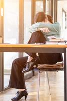 A businessman who is tired and stressed from continuous work for a long time is laying down her head on her arm to relieve stress. The concept of stress caused by long periods of work. photo