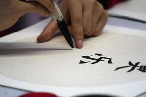 japanese woman writing name Charles in ideograms with brush photo