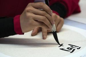 japanese woman writing name Diana in ideograms with brush photo