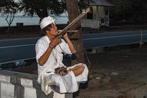 BALI, INDONESIA - AUGUST 12, 2016 - Balinese monk with trigger for monkeys at the temple photo