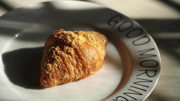 Top view of two croissants placed in a round ceramic dish lying on it in the morning video