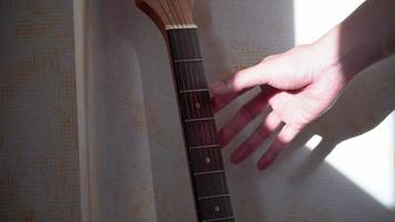 man's hand picked up an acoustic guitar in the evening sun. video
