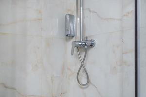 water tap and shower in bathroom on wall with tiles. photo