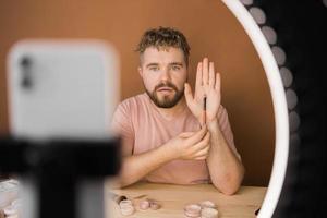 Male beauty blogger doing his make up and recording a video lesson his with mobile phone - vlog, diversity and video blog concept photo