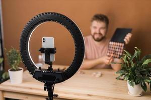 Man recording video vlog while applying cosmetics or explore cosmetic product. Guy making tutorial make-up for his blog on cosmetics. photo