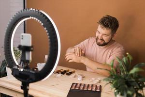 Portrait bearded man making vlog review cosmetics product and channel recording video make up tutorial making at home - Online influencer guy and social media market live steaming concept photo