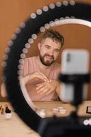 Man vlogging about make up and beauty products. Male shooting a makeup tutorial. Guy teaching make up tutorial using her phone - diversity and blogger concept. photo