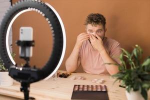 Man recording video vlog while applying cosmetics or explore cosmetic product. Guy making tutorial make-up for his blog on cosmetics. photo