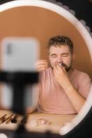 Man recording video vlog while applying cosmetics or explore cosmetic product. Guy making tutorial make-up for his blog on cosmetics. photo