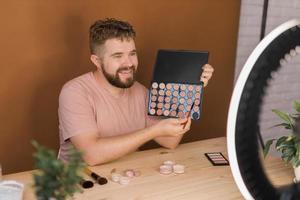 Man recording video vlog while applying cosmetics or explore cosmetic product. Guy making tutorial make-up for his blog on cosmetics. photo