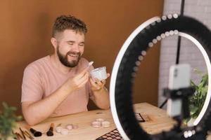 Man recording video vlog while applying cosmetics or explore cosmetic product. Guy making tutorial make-up for his blog on cosmetics. photo