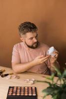 Man vlogging about make up and beauty products. Male shooting a makeup tutorial. Guy teaching make up tutorial using her phone - diversity and blogger concept. photo