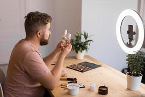Man recording video vlog while applying cosmetics or explore cosmetic product. Guy making tutorial make-up for his blog on cosmetics. photo