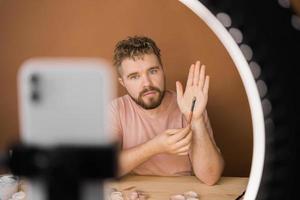 Bearded man professional beauty make up artist vlogger or blogger recording makeup tutorial to share on website or social media. photo