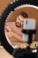 Famous blogger. Cheerful male vlogger showing cosmetics products while recording video and giving advices for his beauty blog. Make-up artist and recording beauty vlog concept photo