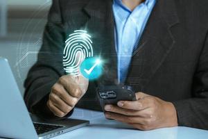 A user accesses document data via a laptop and smartphone equipped with a fingerprint scanner and check mark. Cyber security and data protection information privacy internet photo