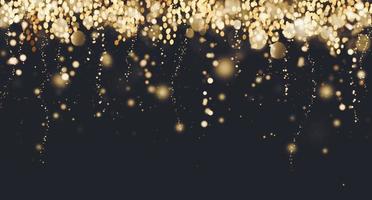 Golden particles border, falling glittering gold sparkles on black background, blurry festive lights, Christmas banner design, copy space photo