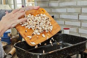 Cook throws mushrooms into square frying pan photo