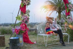 Beautiful young mother daughter sits and relax at summer meadow background and windmills, windmills as alternative energy sources, sustainable resource concept, community people with windmills photo