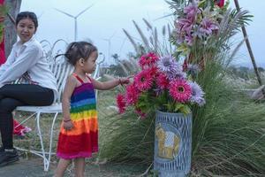 Beautiful young mother daughter sits and relax at summer meadow background and windmills, windmills as alternative energy sources, sustainable resource concept, community people with windmills photo