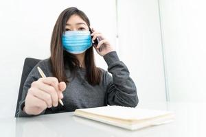 Woman long hair wearing protective mask holding and using mobile phone photo