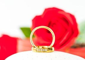 Red roses and gold rings on white photo