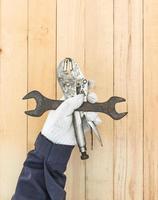 Hand in glove holding Spanner and Adjustable wrench photo