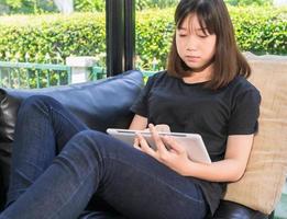 niña estudiando en línea desde una tableta digital en la sala de estar foto