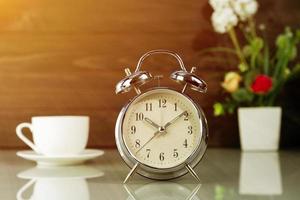 Coffee cup and alarm clock on table photo