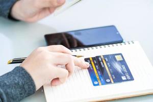 Woman writing on notebook with credit card and smartphone  desk photo