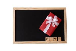 Red gift box and letter words of give on the black board on pink background. photo