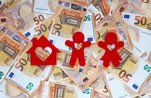 Red felt small house, silhouette of men and women with heart-shaped holes cut out in all of them on 50 fifty euro banknotes background. Home loan for a young couple. Money for family dream house. photo