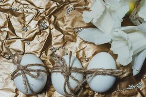 White Easter eggs with flowers on golden background, close up photo