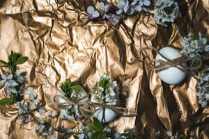 White Easter eggs with flowers on golden background, close up photo