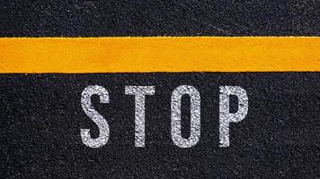 Stop text written and yellow line on the road in middle of the asphalt road, Stop word on street. photo