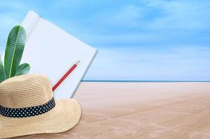 cuaderno con lápiz y Paja sombrero en mar y arena de un playa naturaleza paisaje antecedentes foto