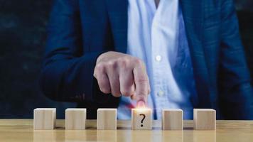 Businessman hand choose the wooden block with Questions Mark on wooden cube block on table ,FAQ frequency asked questions, Answer, Q and A, Information, Communication and interrogation Concepts