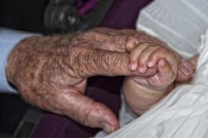 old retired man hands holding newborn infant one photo