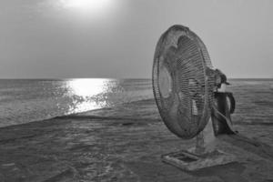 A old used fan near the sea in black and white photo